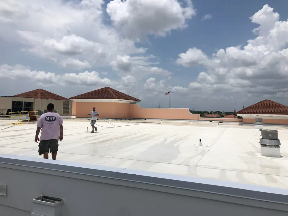 Crew applying a reflective coating to a flat roof